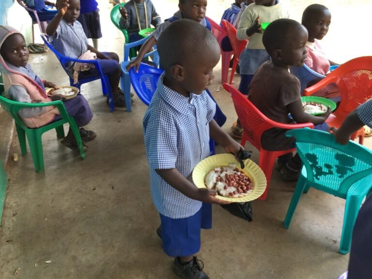Children seated together with prepared meals at a Friends of Dago feeding activity