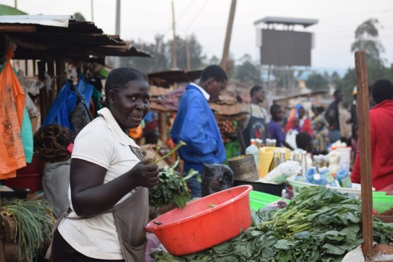 Woman arranging leafy vegetables at a market stall